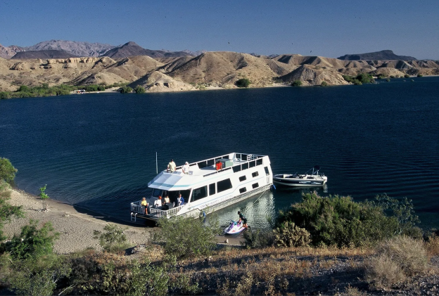 houseboat and jet ski docked on a beach
