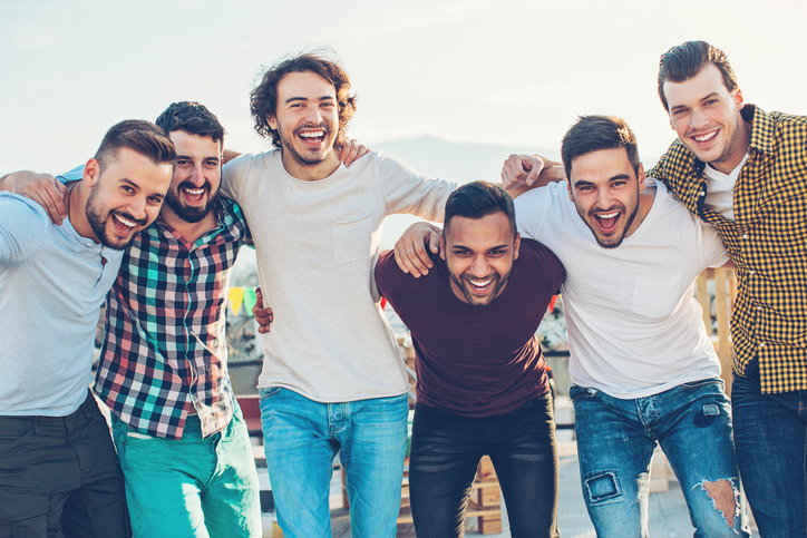 Multi-ethnic group of young men holding together and laughing.