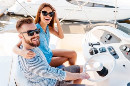 Top view of young couple looking at camera and smiling while driving boat rental at lake mead