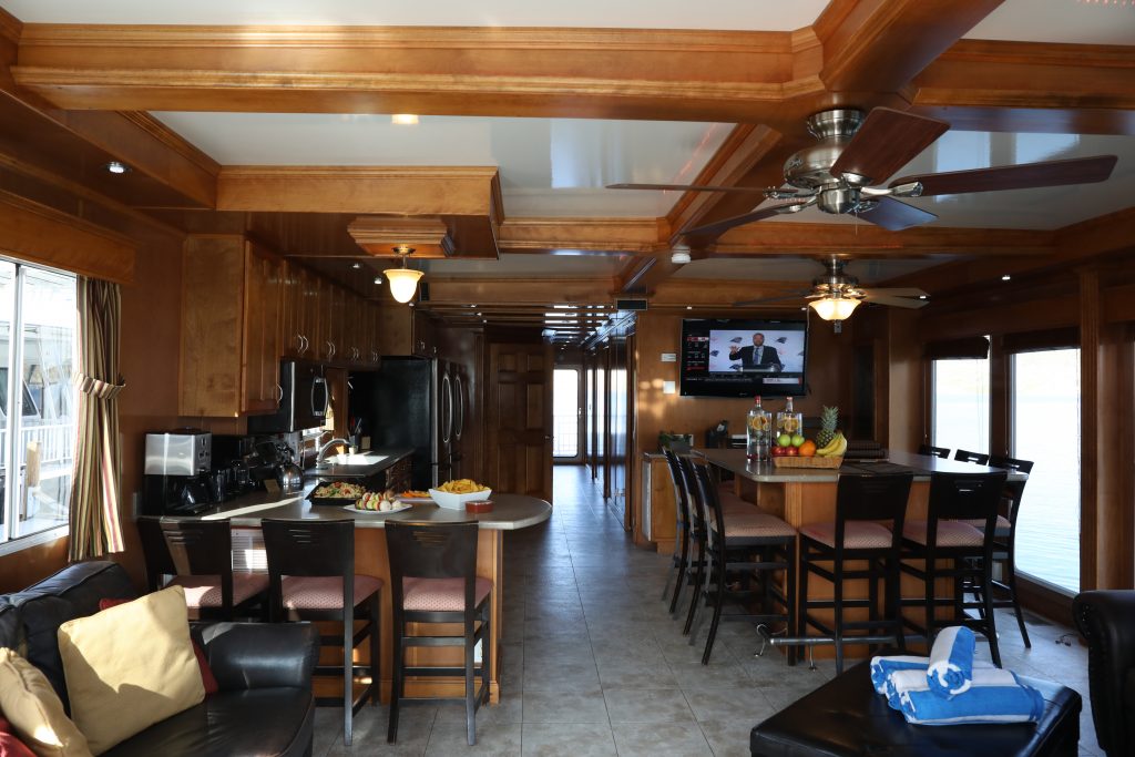 large houseboat inside with wood features, large hightop dining room table, kitchen with breakfast bar and a sofa