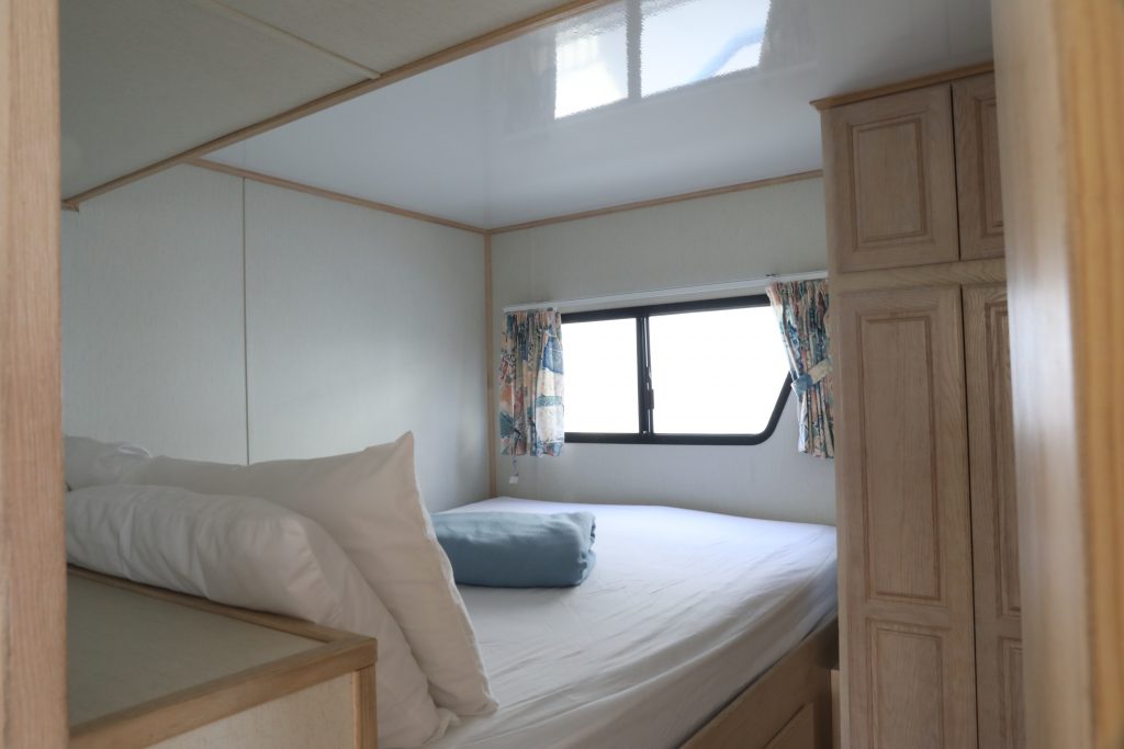 inside small houseboat room with queen size bed and cabinets