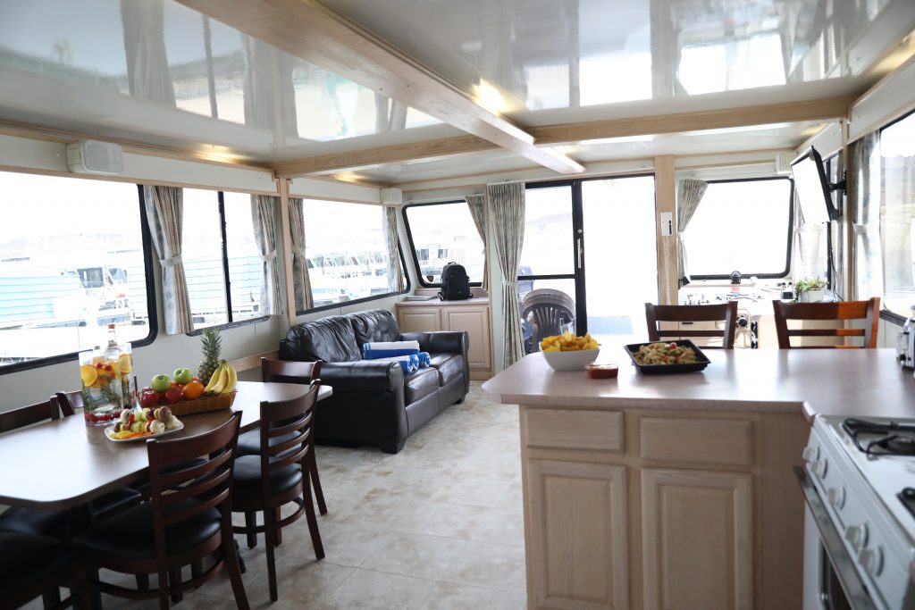 large houseboat inside, with a table and chairs, a sofa, dining area and kitchen counter